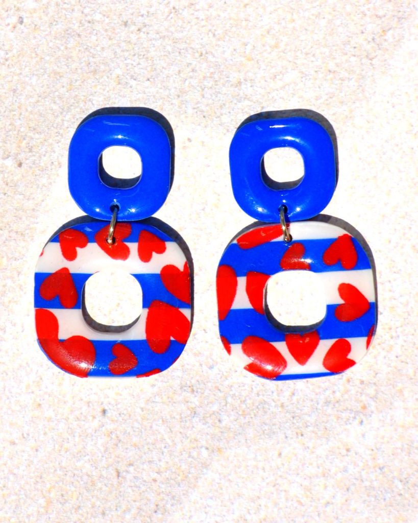 Paire de boucles d'oreilles duo de carrés aux bords arrondis. Un petit carré bleu éclatant surmonte un plus gros carré marinière à cœurs rouges.