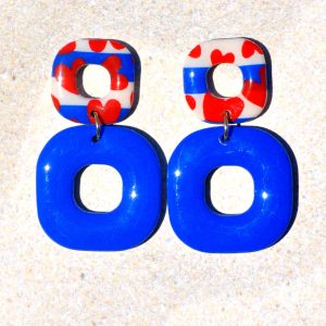 Paire de boucles d'oreilles duo de carrés aux bords arrondis. Un petit carré marinière à cœurs rouges, surmonte un plus gros carré uni bleu éclatant.