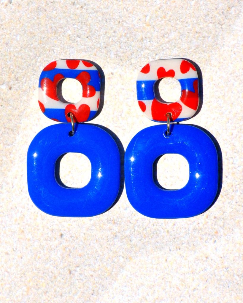 Paire de boucles d'oreilles duo de carrés aux bords arrondis. Un petit carré marinière à cœurs rouges, surmonte un plus gros carré uni bleu éclatant.