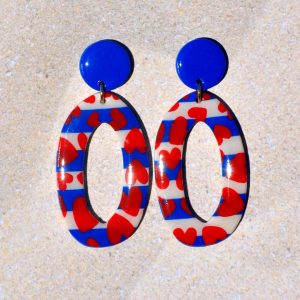 Paire de boucles d'oreilles en deux parties. Une puce ronde unie bleue éclatante surmonte un ovale long très ajouré, au motif marinière cœurs rouges.