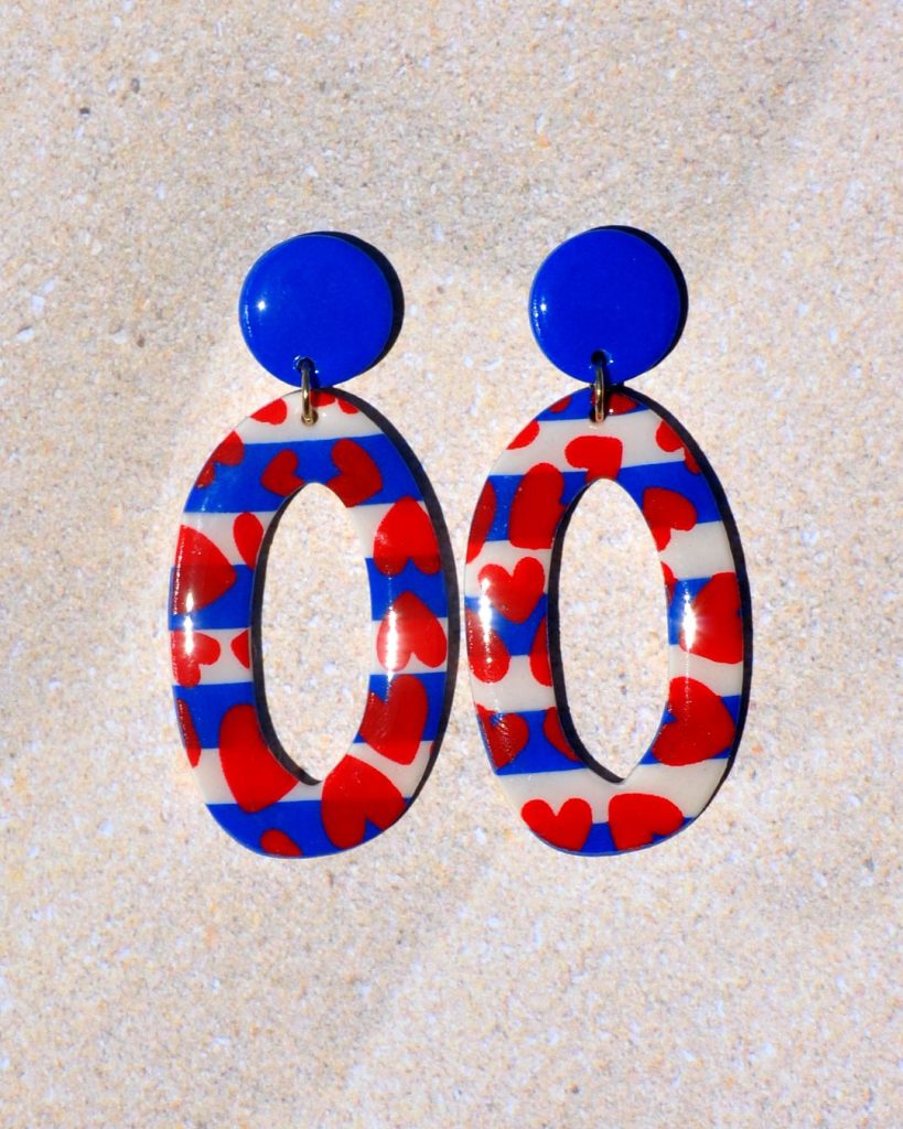 Paire de boucles d'oreilles en deux parties. Une puce ronde unie bleue éclatante surmonte un ovale long très ajouré, au motif marinière cœurs rouges.