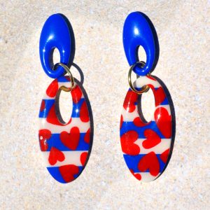 Paire de boucles d'oreilles duo d'ovales allongés et ajourés. Un petit ovale bleu éclatant surmonte un plus gros ovale marinière à cœurs rouges.