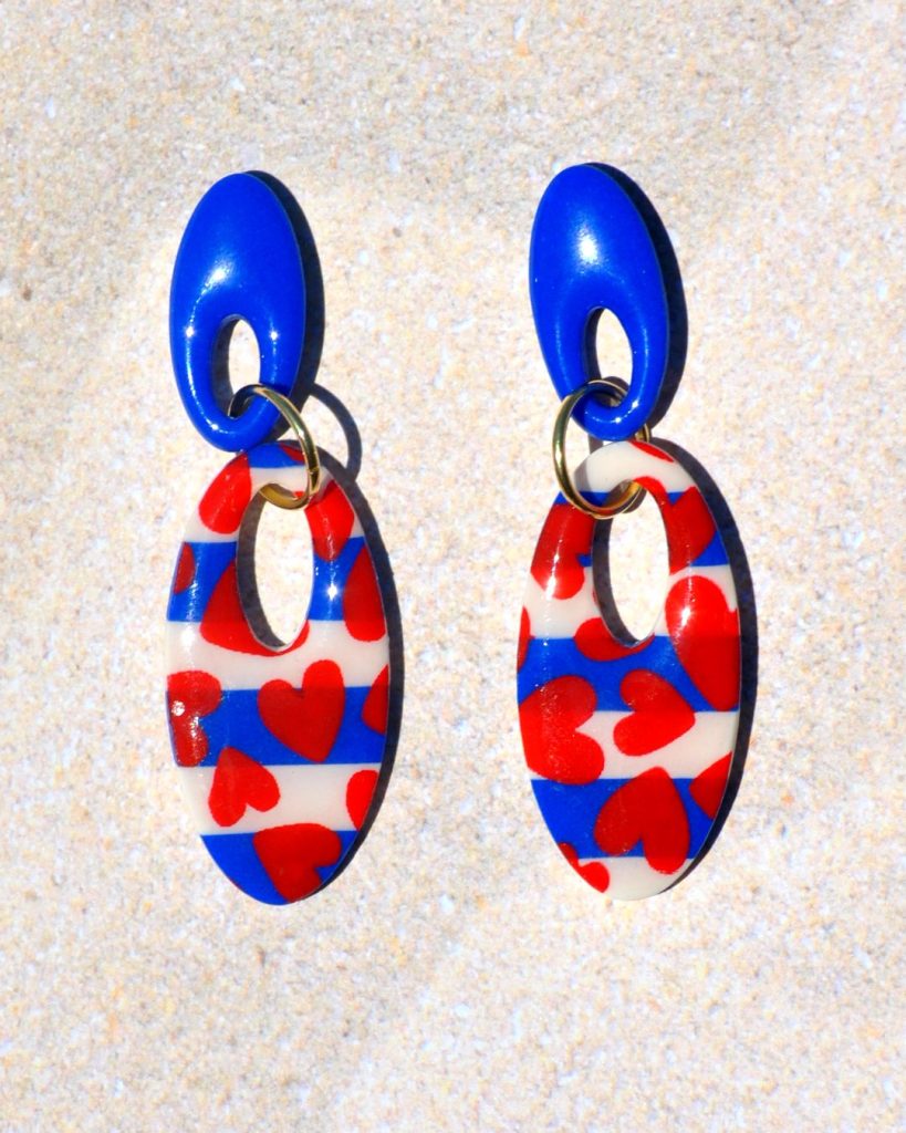 Paire de boucles d'oreilles duo d'ovales allongés et ajourés. Un petit ovale bleu éclatant surmonte un plus gros ovale marinière à cœurs rouges.